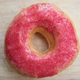 A ghost pepper donut covered in pink frosting and red sprinkles